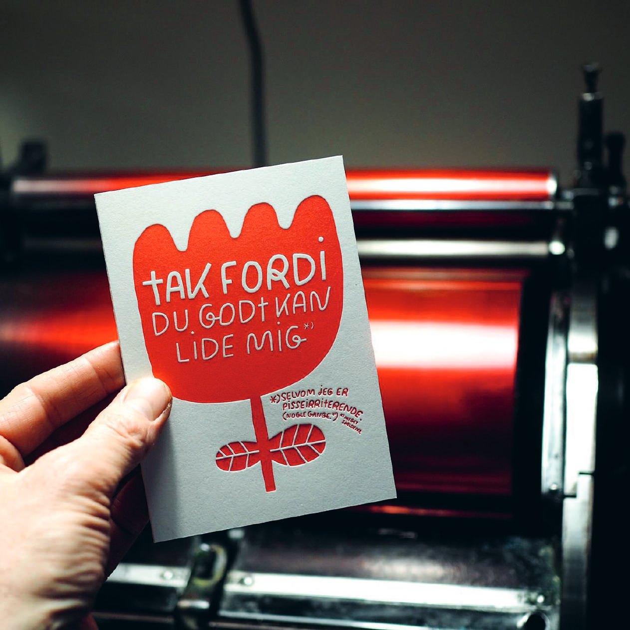 Tak fordi card, red tulip, held in front of the press