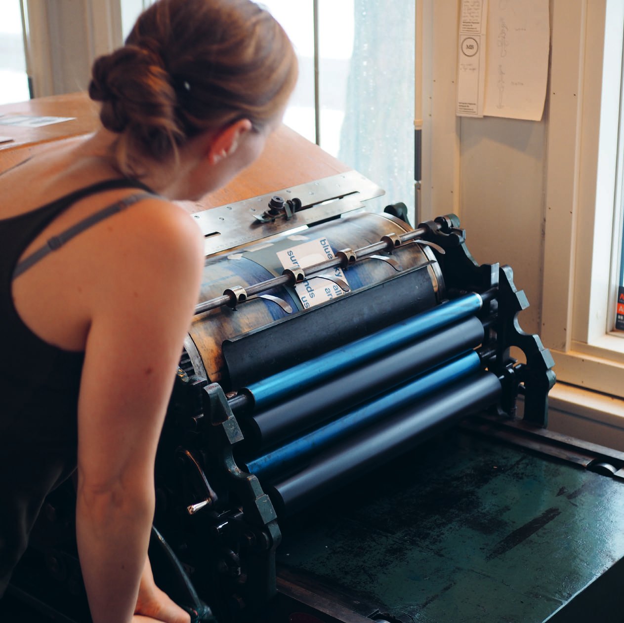 Printer leaning over the rollers of a press